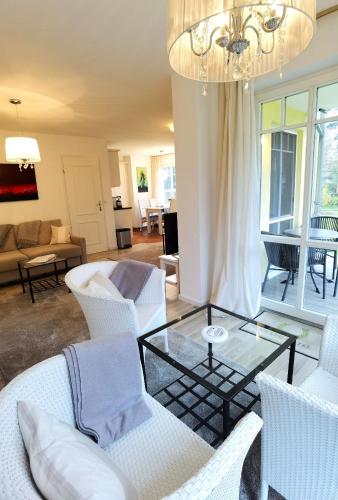 a living room with white chairs and a glass table at Ferienwohnung Elke am Kurfürstensteg in Bad Saarow