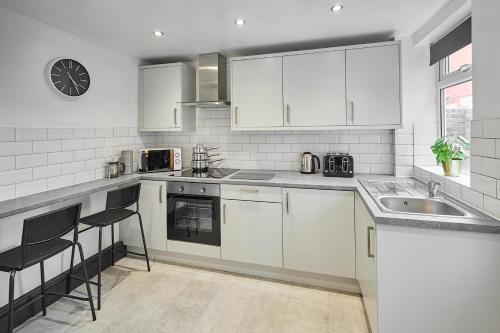 a kitchen with white cabinets and a sink at Host & Stay - Rathbone Road in Liverpool