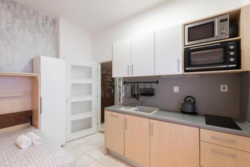 プラハにあるLotus Apartmentの白いキャビネット、シンク、電子レンジ付きのキッチンが備わります。