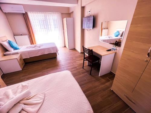 Habitación con 2 camas y escritorio con espejo. en Figen Suite Hotel 2, en Canakkale