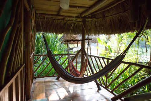 a hammock hanging from a straw roofed porch at El Hotelito Perdido in Rio Dulce