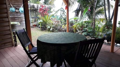 a table and chairs on a porch with a garden at Le gîte du pêcheur in La Trinité