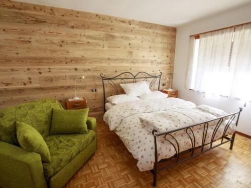 una camera con letto e divano verde di affittacamere li di Giuan a Lauco
