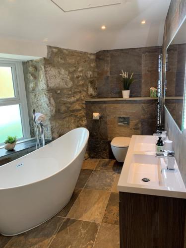 a bathroom with a large white tub and a toilet at Modern studio apartment with stunning views! in St Ives