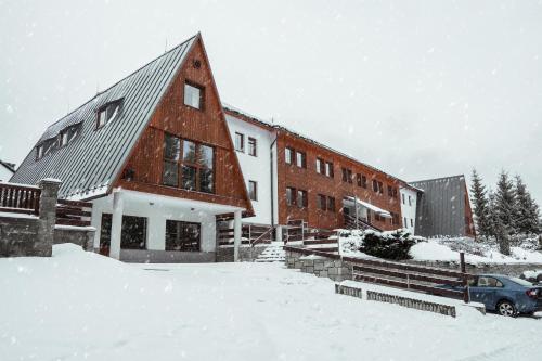 un bâtiment avec une voiture garée dans la neige dans l'établissement Horský hotel Brans, à Malá Morávka