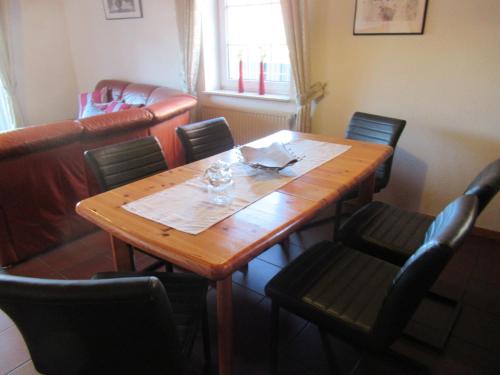 einen Holztisch und Stühle in einem Zimmer mit einem Tisch und einem Chairsktop in der Unterkunft Ferienhaus Strandfuchs, Hooksiel in Wangerland
