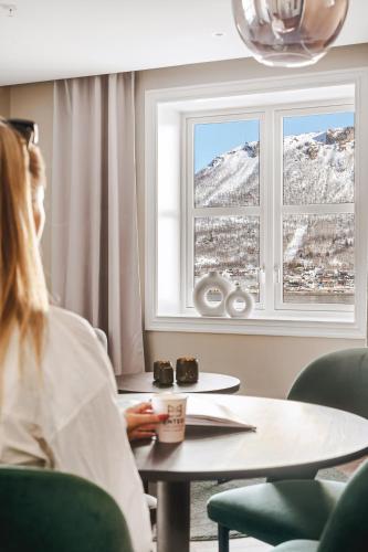a woman sitting at a table looking out a window at Enter St Elisabeth Suites & Spa in Tromsø