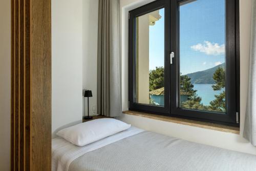 a bedroom with a window with a view of a lake at Archetypo Luxury Living in Chrysi Ammoudia