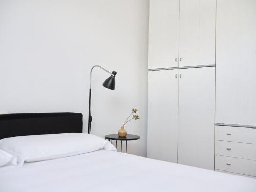 a white bedroom with a bed and a lamp at APPARTAMENTO GHITA in Baveno