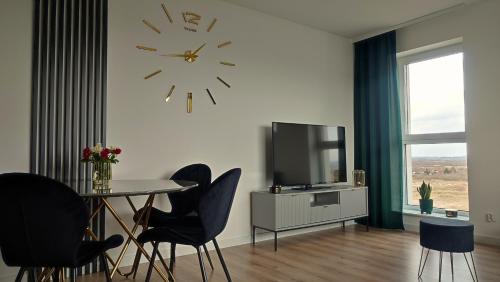 a dining room with a table and a clock on the wall at Apartament Szmaragdowy Light Tower Aquapark Reda in Reda