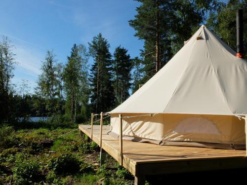 a white tent sitting on top of a wooden deck at Frisbo Lodge - Glamping tent in a forest, lake view in Bjuråker