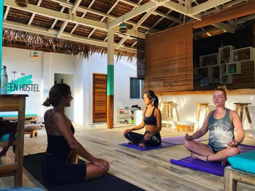 three women sitting in a yoga pose in a room at Green Soul Port Barton in San Vicente