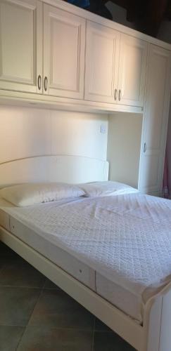 a white bed in a room with white cabinets at Residenze Coda Cavallo in San Teodoro
