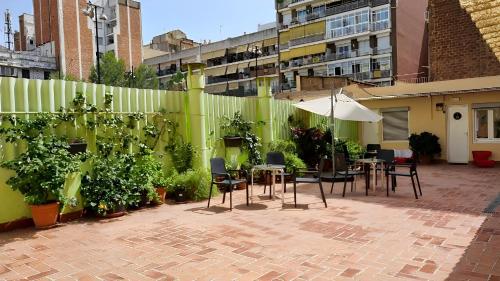 a patio with tables and chairs and a green fence at Paraiso Hostel in Barcelona