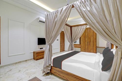 a bedroom with a bed with curtains and a television at Ratna Vilas Palace in Rajkot