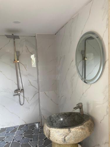 a bathroom with a stone sink and a mirror at Ngọc Tiên Farmer Eco Lodge in Cat Tien