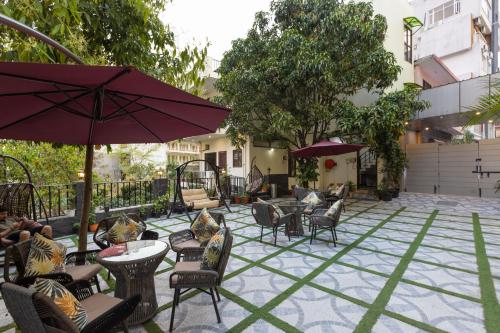 a patio with chairs and tables and an umbrella at Yogved Hospitality & Resort in Rishīkesh