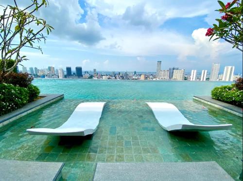 two white chairs sitting in the water near a city at Beacon Executive Suite by stayCATion Homestay in George Town