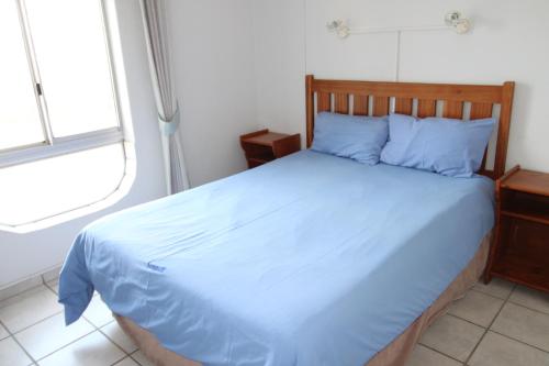 Schlafzimmer mit einem Bett mit blauer Bettwäsche und einem Fenster in der Unterkunft Seagull 203 in Margate