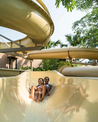 two children sitting on a slide at a water park at New World Hoiana Beach Resort in Hoi An