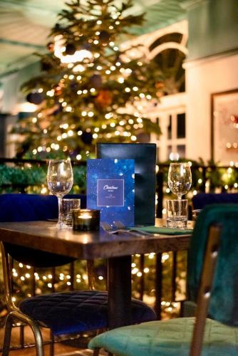 a table with two wine glasses and a christmas tree at The Regency Hotel in Solihull