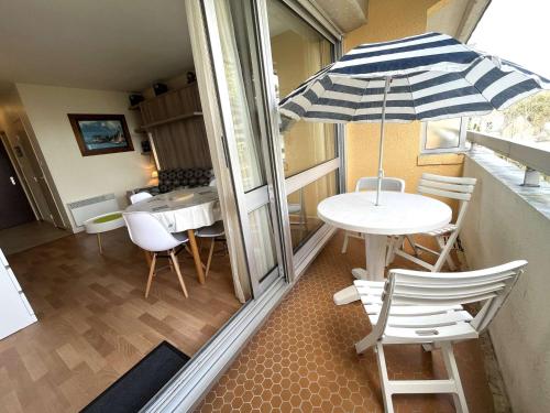 une table et des chaises avec un parasol sur un balcon dans l'établissement Studio cosy à Bénodet: plage, restos, thalasso à pied, balcon et parking privé - FR-1-481-135, à Bénodet