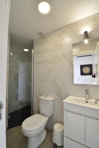 a white bathroom with a toilet and a sink at Sophia Studios in Coimbra