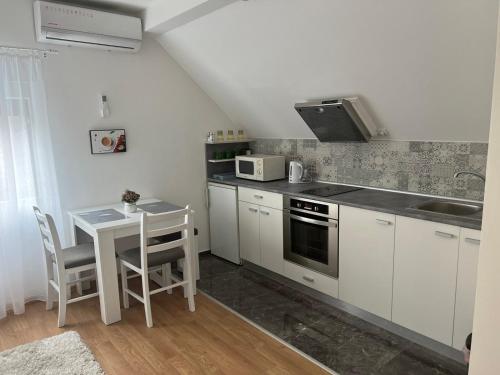 a kitchen with white cabinets and a table with a microwave at Apartman Biki in Banja Koviljača