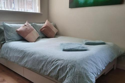 Una cama con almohadas rosas y azules. en Self-contained annex with private entrance, double bed, kitchen, bathroom, free car park - Near Cambridge, Duxford Air Museum and Addenbrooke's Hospital en Cambridge