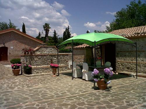 um pátio com um guarda-sol verde e algumas cadeiras em Società Agricola MG Florplant em Francavilla Marittima