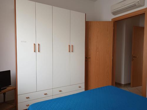 ein Schlafzimmer mit weißen Schränken und einem blauen Bett in der Unterkunft Appartamenti Carlotta in Rimini