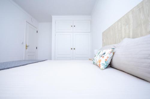 um quarto branco com uma cama grande e uma almofada em Cem Sentido - Alentejo Apartments em Portalegre