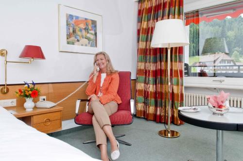 a woman sitting in a red chair talking on a phone at RECHTMURG 27 in Baiersbronn