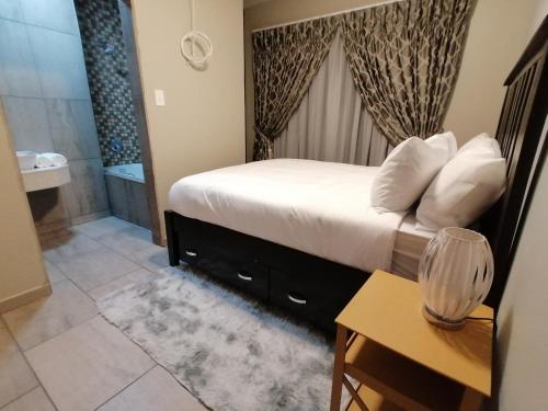 a bedroom with a bed and a bathroom with a tub at Sibebe View Villa in Mbabane