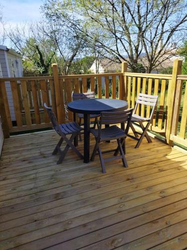 une table et des chaises sur une terrasse en bois dans l'établissement mobile home, à Saint-Christol-lès-Alès