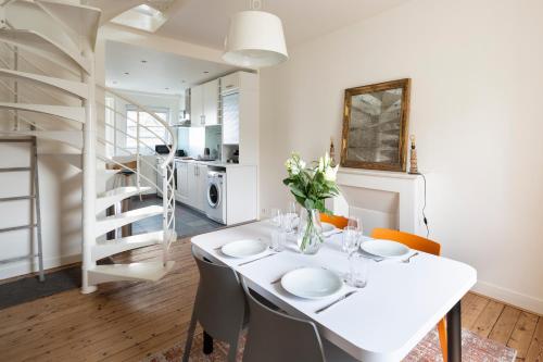 une salle à manger blanche avec une table et des chaises blanches dans l'établissement Les Vigies by Cocoonr, à Saint-Malo