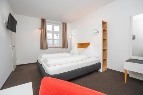 um quarto com uma cama e um sofá vermelho em Klosterbräuhaus Ursberg em Ursberg
