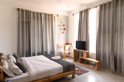 a bedroom with a bed and a tv and curtains at ilaka Homes in Bīr