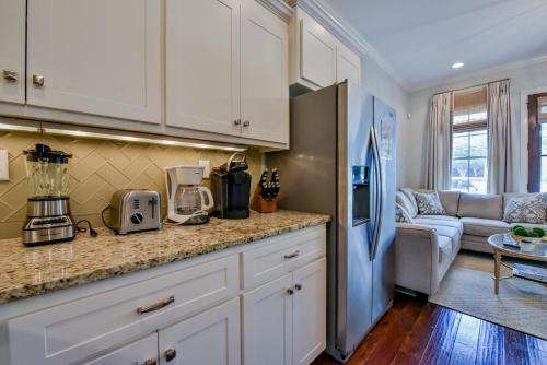 a kitchen with white cabinets and a living room at Bama Getaway in Tuscaloosa