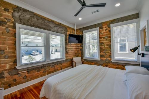 a brick walled bedroom with a bed and windows at The Magnolia in Tuscaloosa