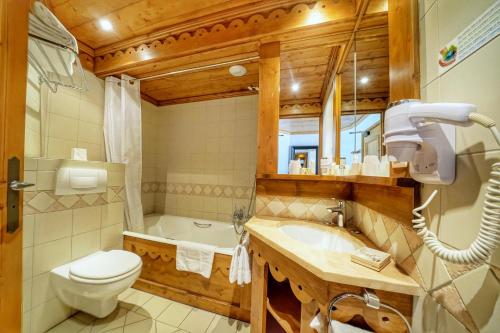 uma casa de banho com um WC, uma banheira e um lavatório. em Au Vieux Moulin em Megève