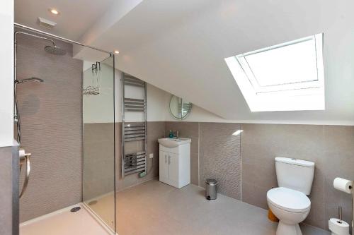 a bathroom with a shower and a toilet and a skylight at Finest Retreats - The Roost in Stamford