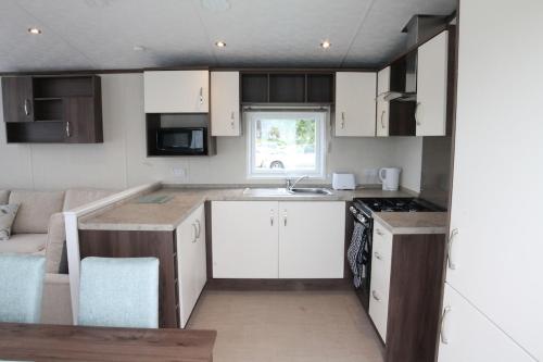 a small kitchen with white cabinets and a sink at Countryside Holiday Park by the River nr Canterbury (Pet-Friendly) in Canterbury