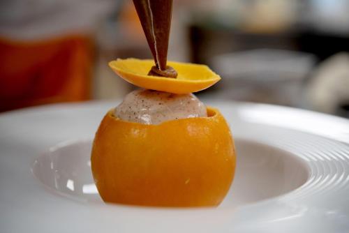a knife cutting into an orange on a white plate at Logis Restaurant & Hôtel À la 12 in Delme