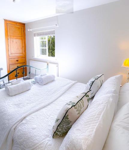 a bedroom with a large white bed with pillows at Carrow Cottage in Ironbridge