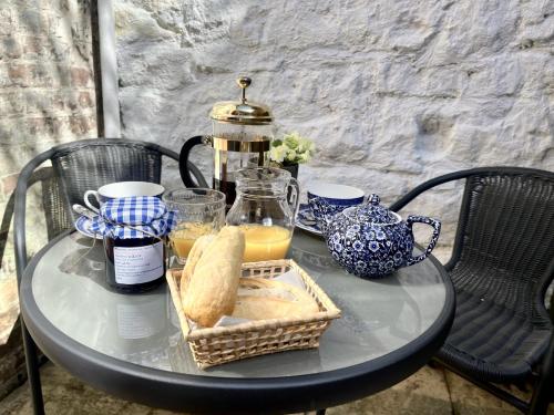 a glass table with a breakfast of bread and orange juice at Carrow Cottage in Ironbridge