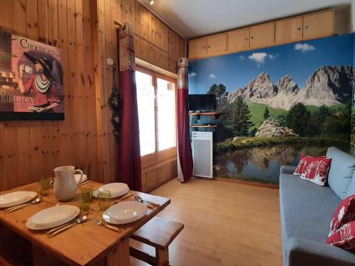une salle à manger avec une table et une fresque murale. dans l'établissement Studio Montagne Montgenèvre - 5 pers, Balcon Sud, Proche Pistes et Navette - FR-1-330D-3, à Montgenèvre