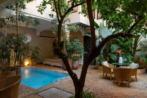 una piscina in un cortile con tavolo e sedie di Riad l'Oiseau du Paradis a Marrakech