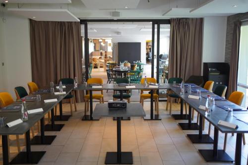 a row of tables in a room with yellow chairs at Campanile Troyes Sud - Buchères in Troyes