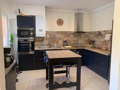 une cuisine avec des placards bleus et une table en bois dans l'établissement Magnifique F3 lumineux avec terrasses, climatisation, garage et WiFi à Amélie-les-Bains - FR-1-703-81, à Amélie-les-Bains-Palalda